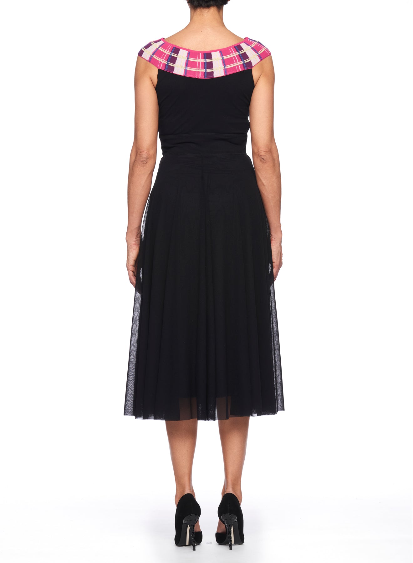 The individual is facing away from the camera, dressed in a Fuzzi Woman Black Dress by Fuzzi. This sleeveless dress boasts a pink and white plaid detail on the shoulders, with a body-hugging fit and a flowing, knee-length skirt. They are paired with black heels.